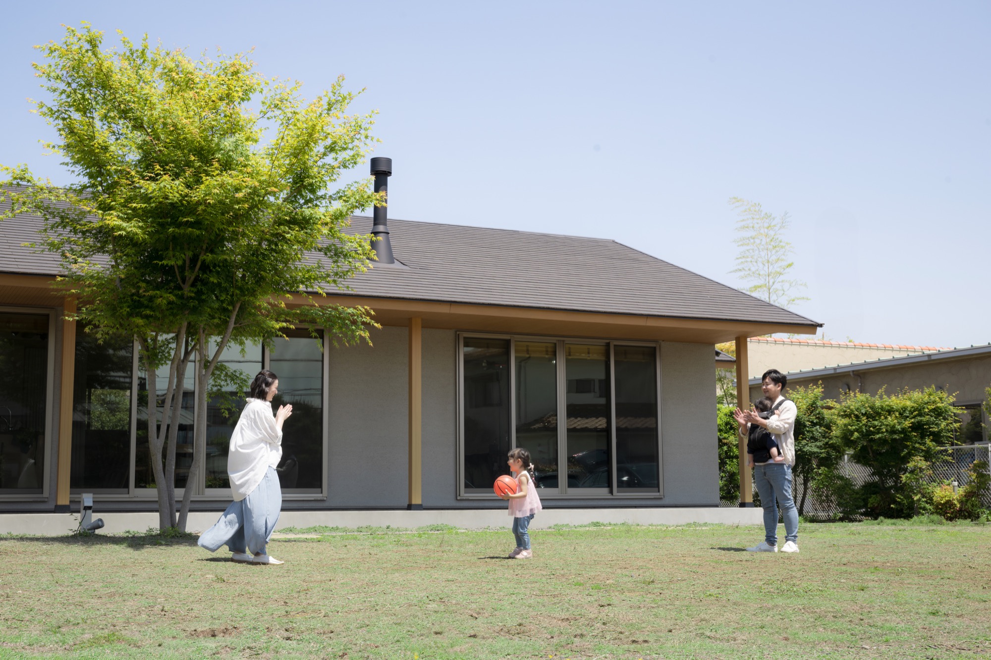 平屋住宅の庭でボール遊びを楽しむ親子
