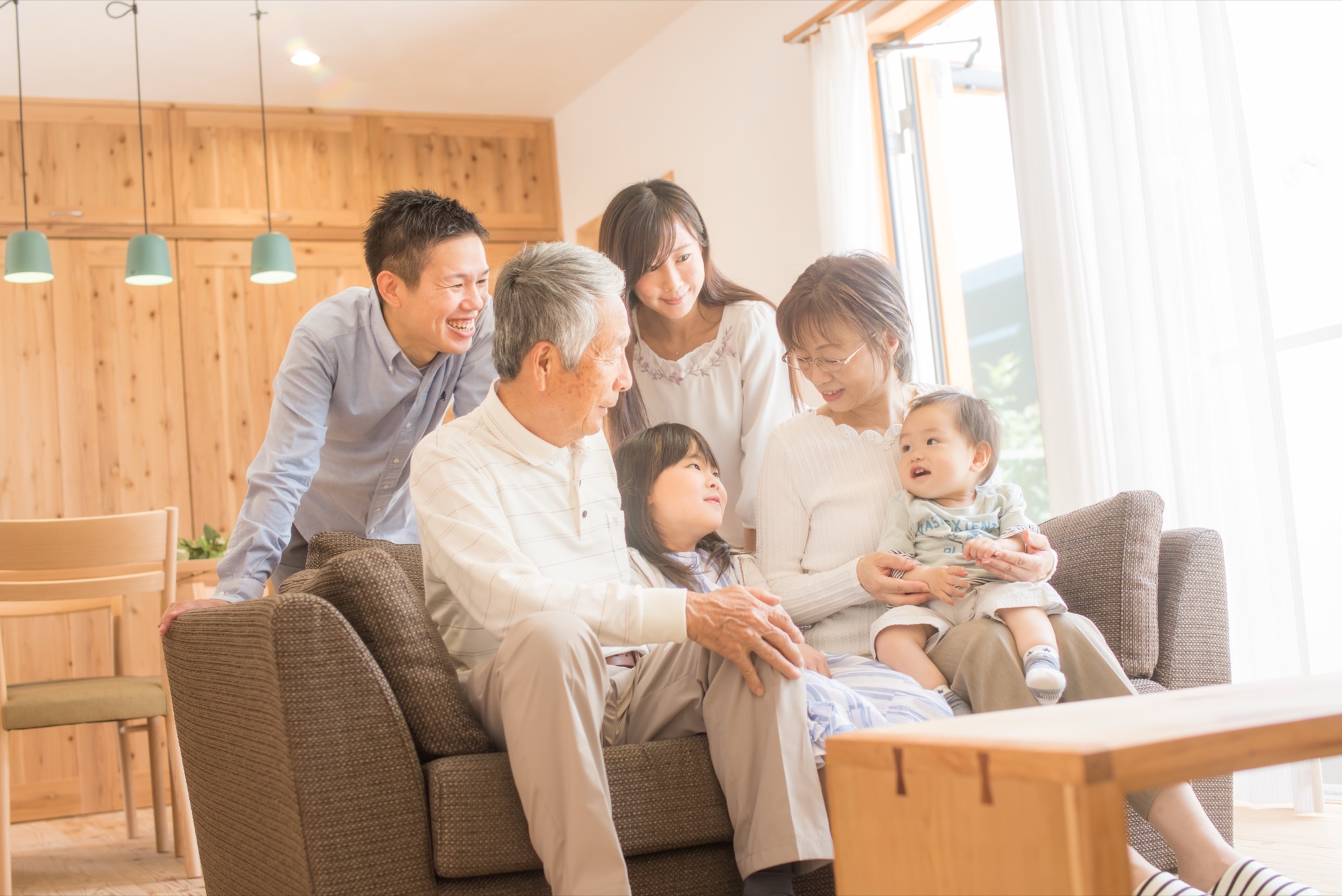 自宅のリビングでくつろぐ三世代家族のイメージ