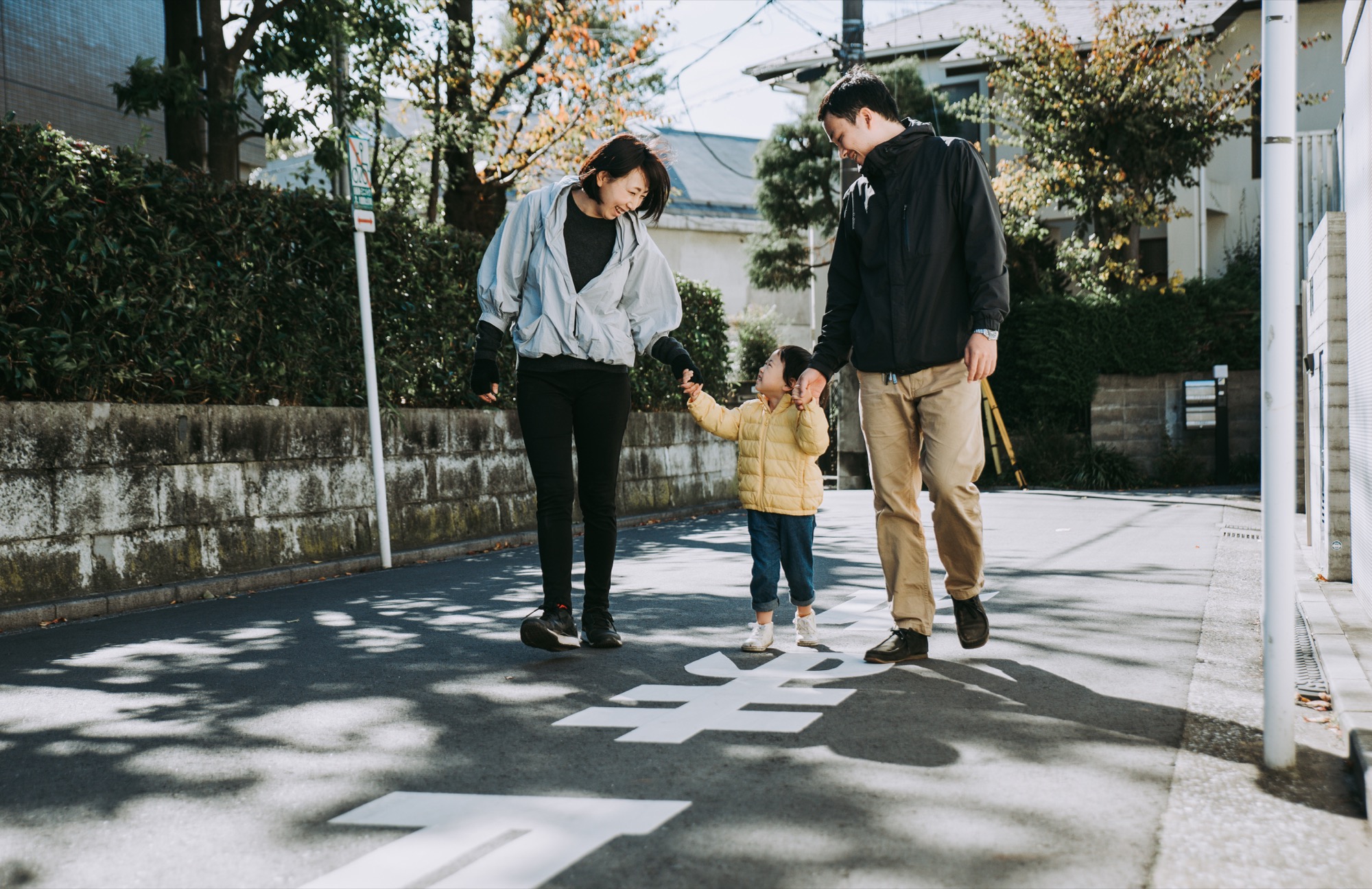 都市部の住宅地で散歩を楽しむ小さな子どもと両親