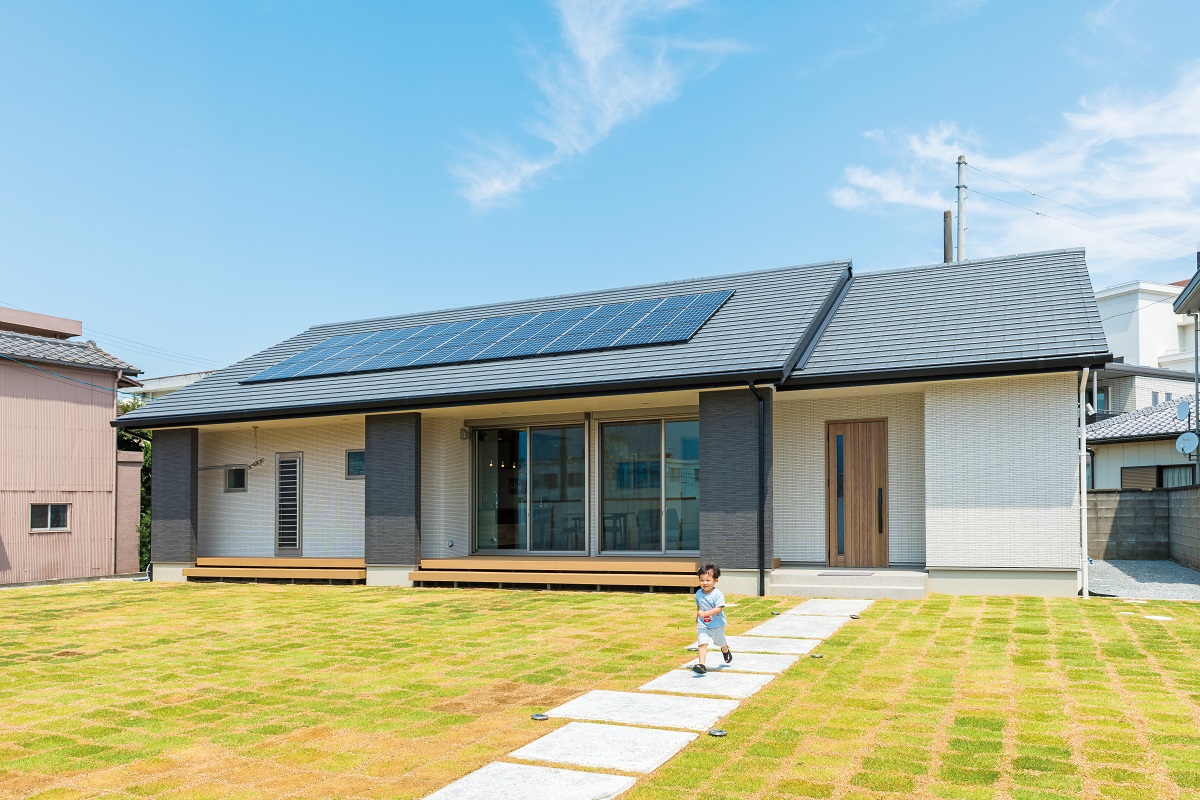 広大な敷地に立つ新築平屋住宅と庭を走る子ども