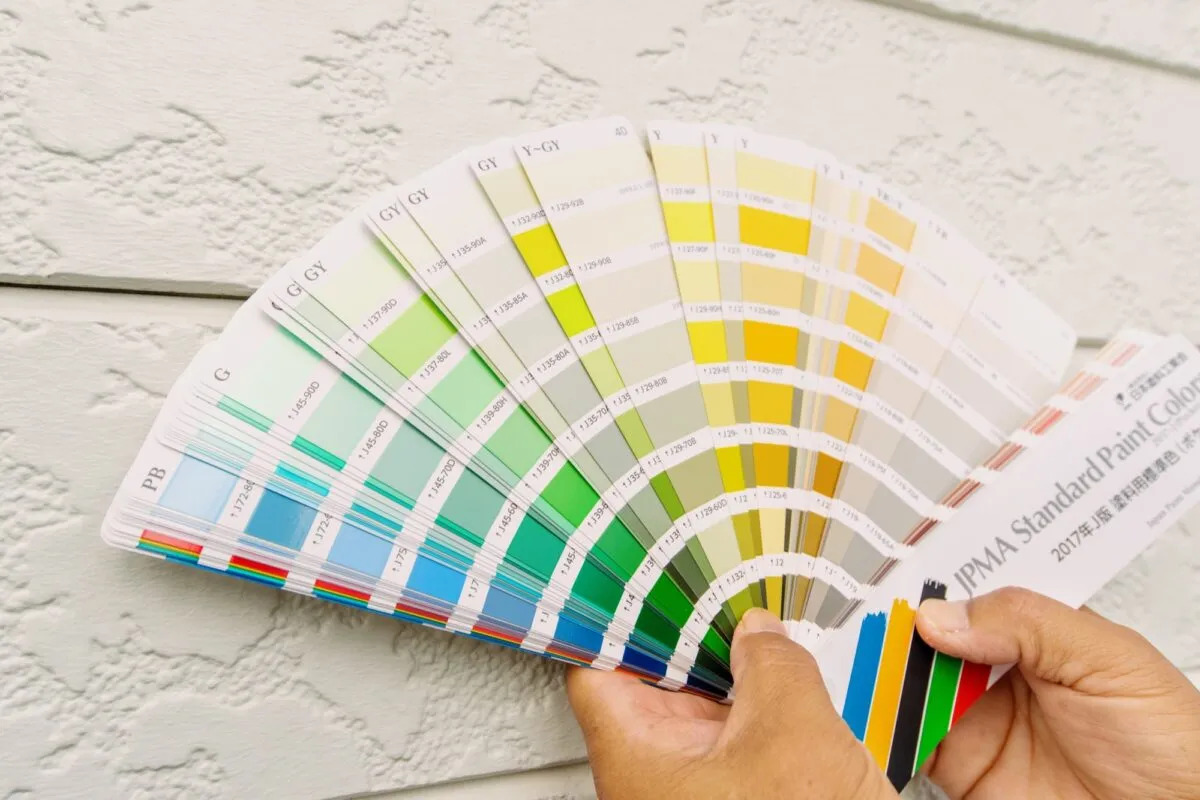 カラーパレットを広げて外壁の色を検討する男性の手元