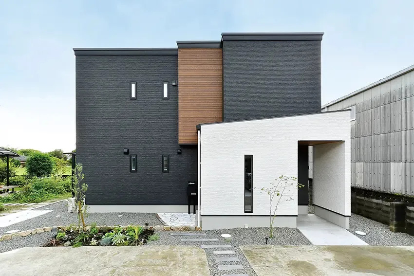 白黒のモノトーン外壁に、ブラウンのワンポイントと整えられた植栽が映える注文住宅の外観