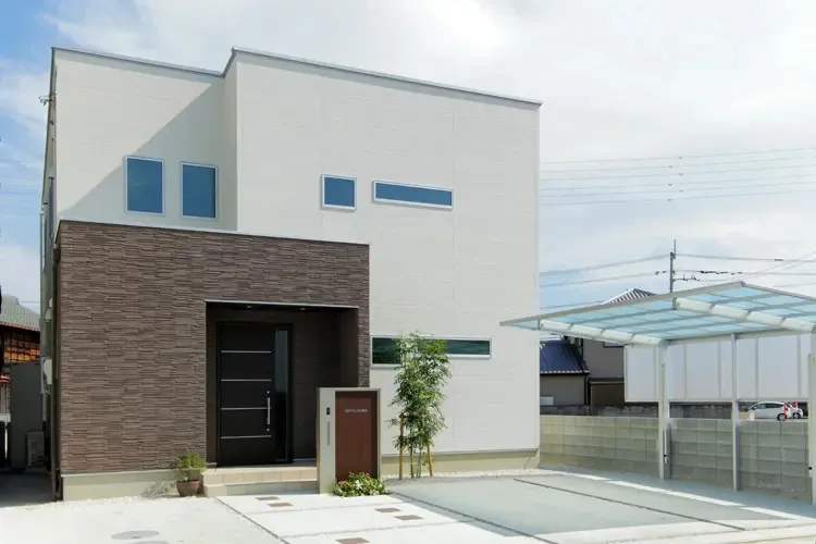 白をベースに、玄関周りにブラウンのタイル外壁を施したナチュラルモダンな注文住宅の外観