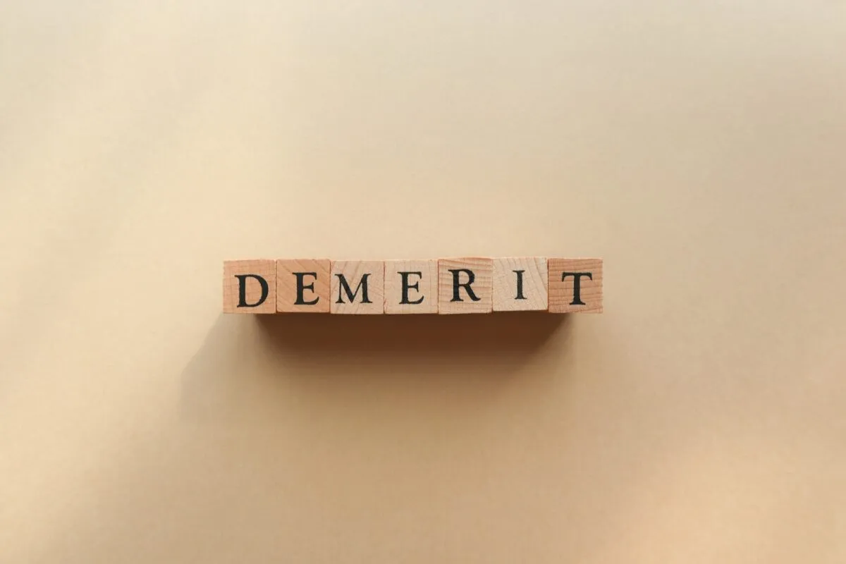 「DEMERIT」と並べられた木の文字ブロック