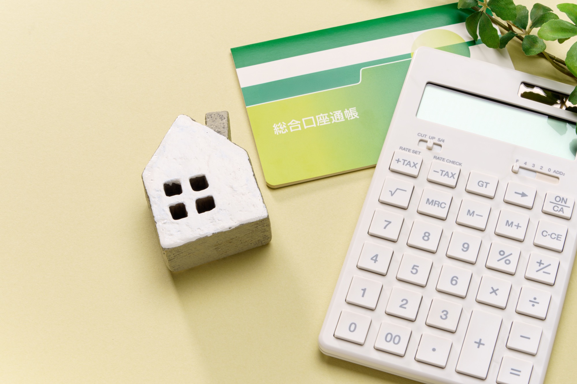 住宅模型、電卓、預金通帳で表した年収倍率のイメージ