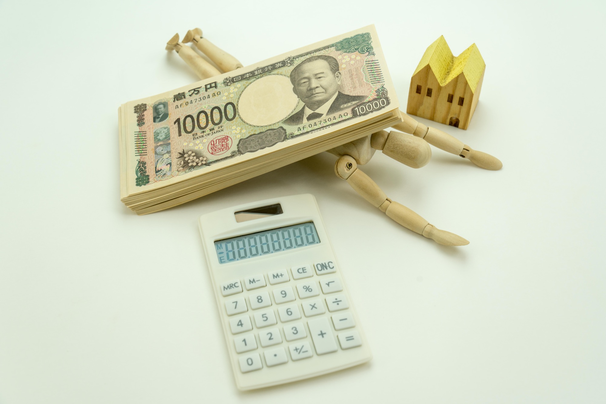 1万円札の札束の下敷きになった人形と電卓
