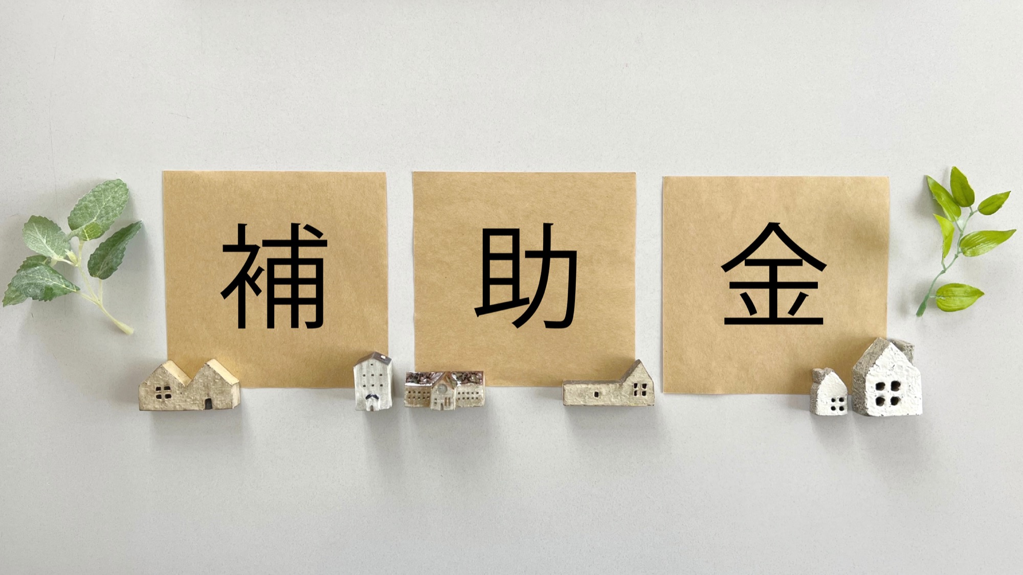 補助金と書かれた紙、家の小物で表した住宅補助金のイメージ