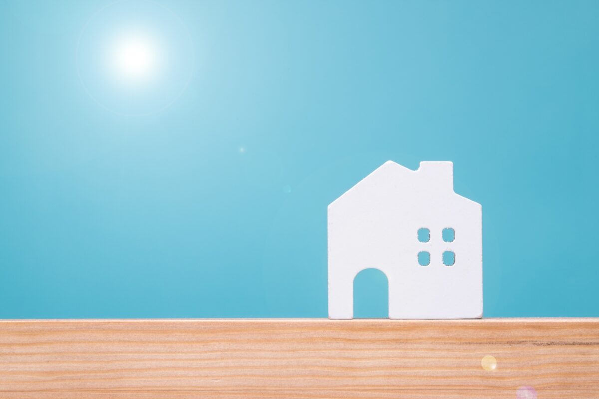 白い住宅模型と太陽で表現したパッシブデザインのイメージ