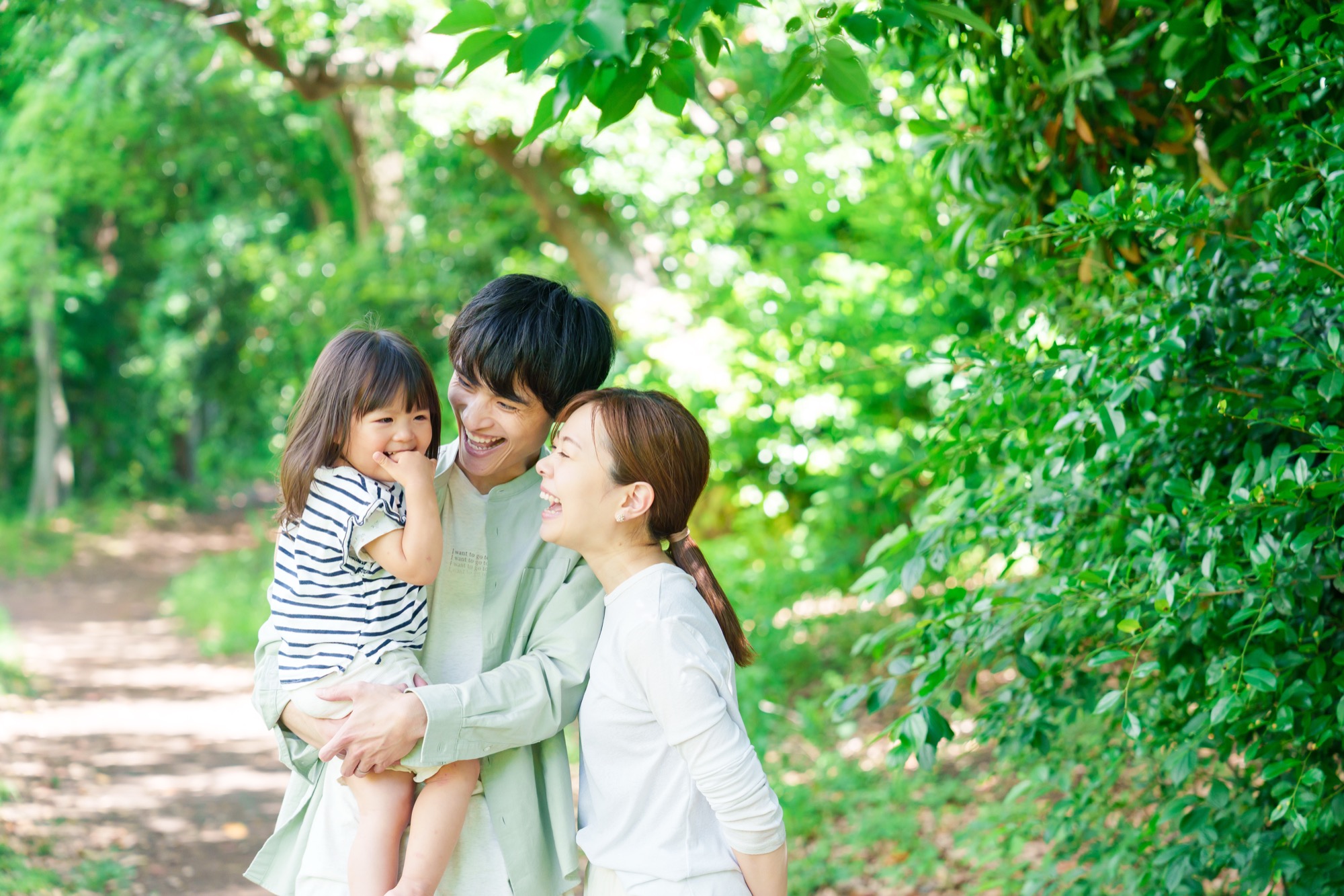 森の小道で笑い合う両親と小さな女の子