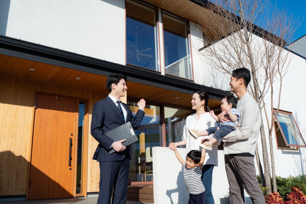 モデルハウスを見学しにきた4人家族を案内するスーツ姿の男性