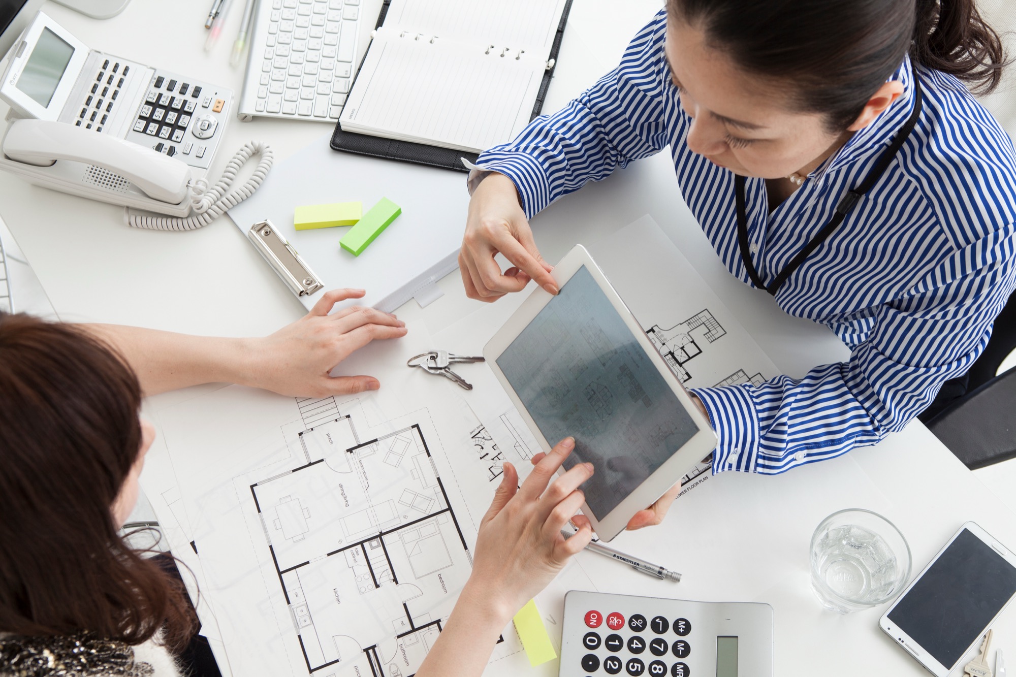 顧客にタブレット端末を見せながら、建築プランを説明する女性