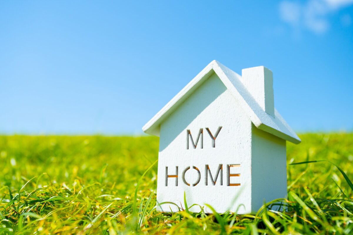 青い空、芝生の上にあるMY HOMEと書かれた白い住宅模型