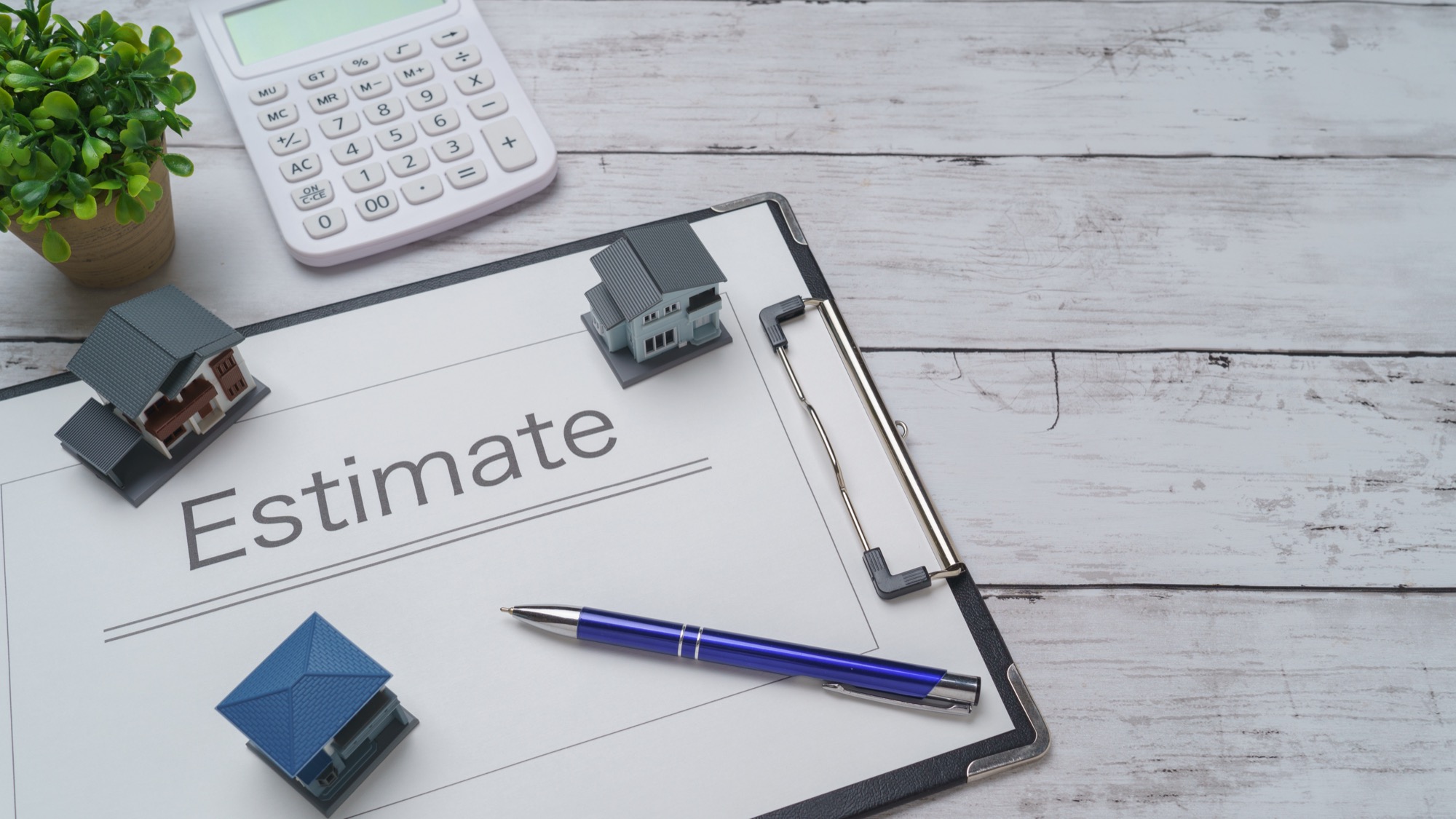 見積書の上に置かれた3つの住宅模型、近くにある電卓