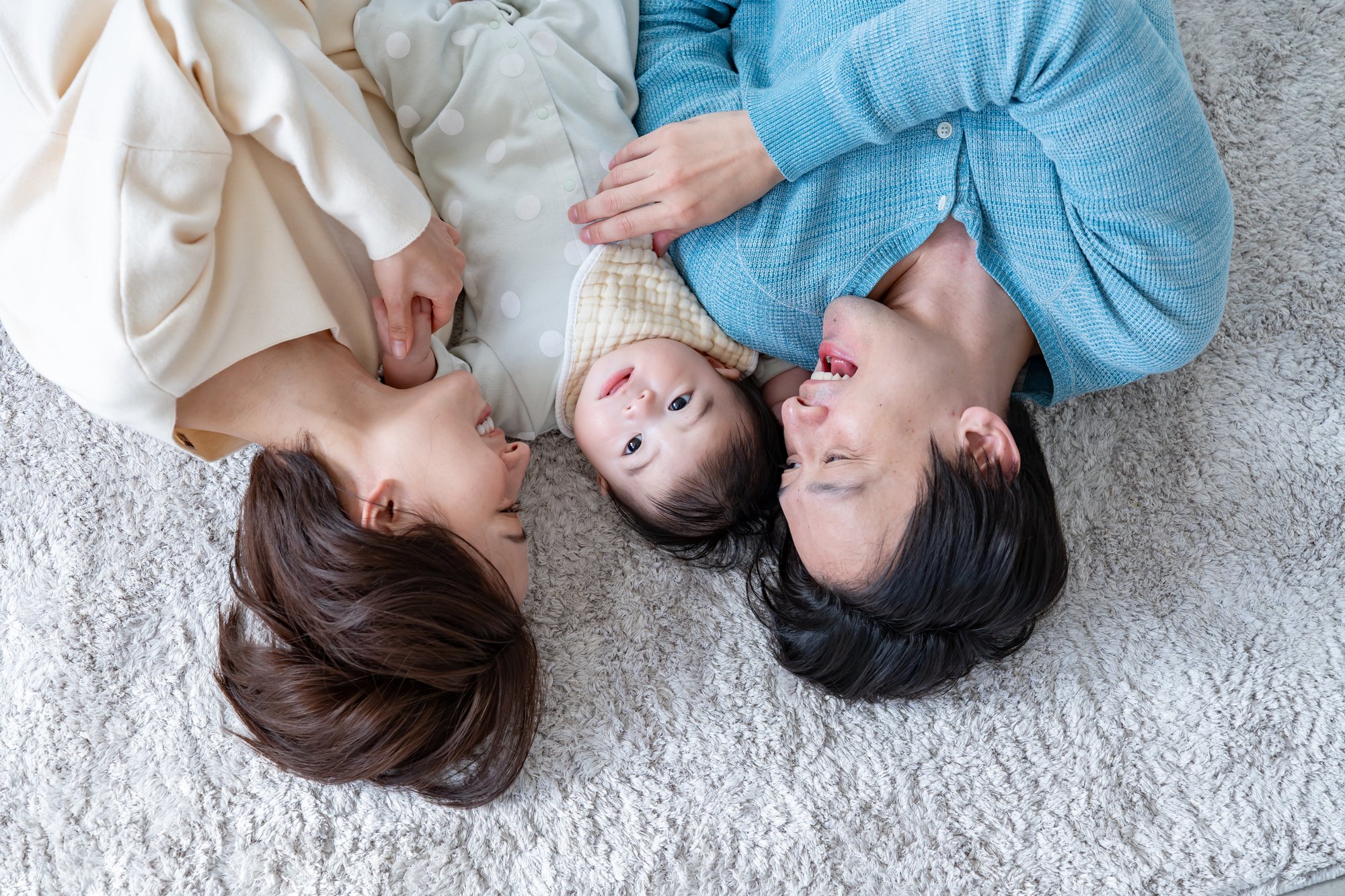冬でも暖かい家で寝転ぶ両親と赤ちゃん