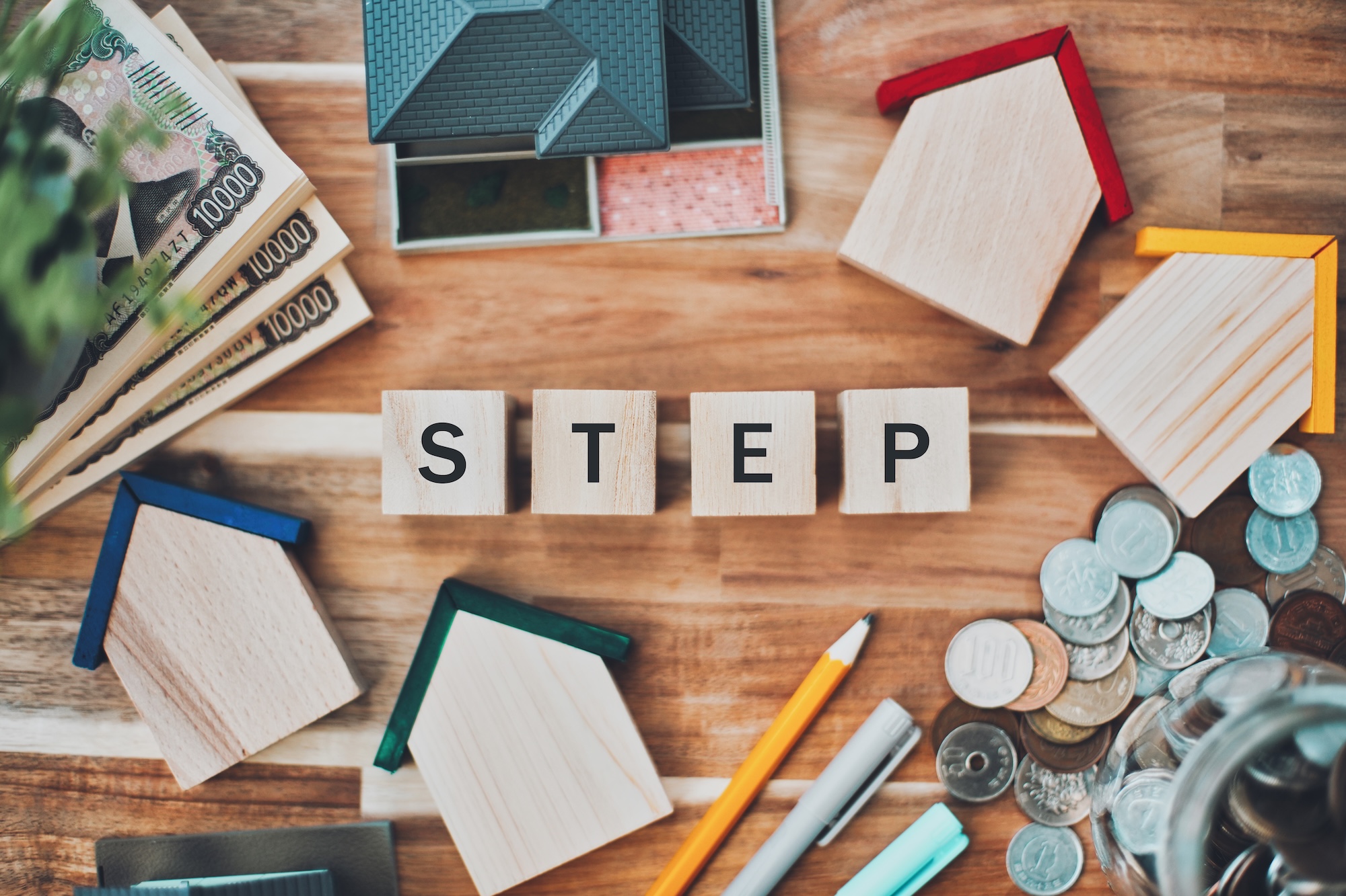 住宅模型や家形ブロック、お金に囲まれた「STEP」の文字ブロック