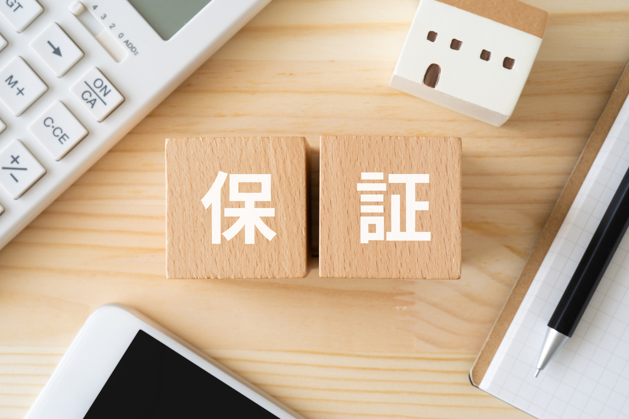 保証と書かれたブロック、電卓、家のおもちゃ